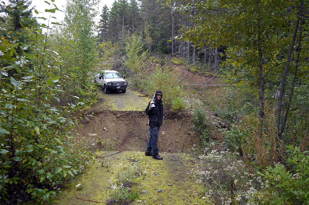Geoff looking at the wide washout that stopped the truck from reaching the end of the road